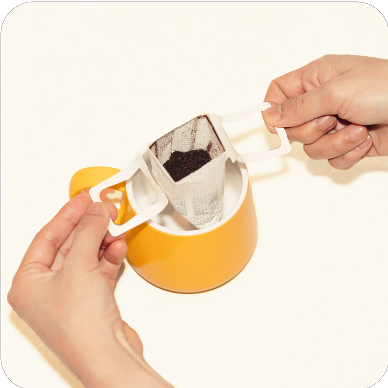 Single serve pour over coffee instruction, second step - open up the wings and hook pouch over a mug 